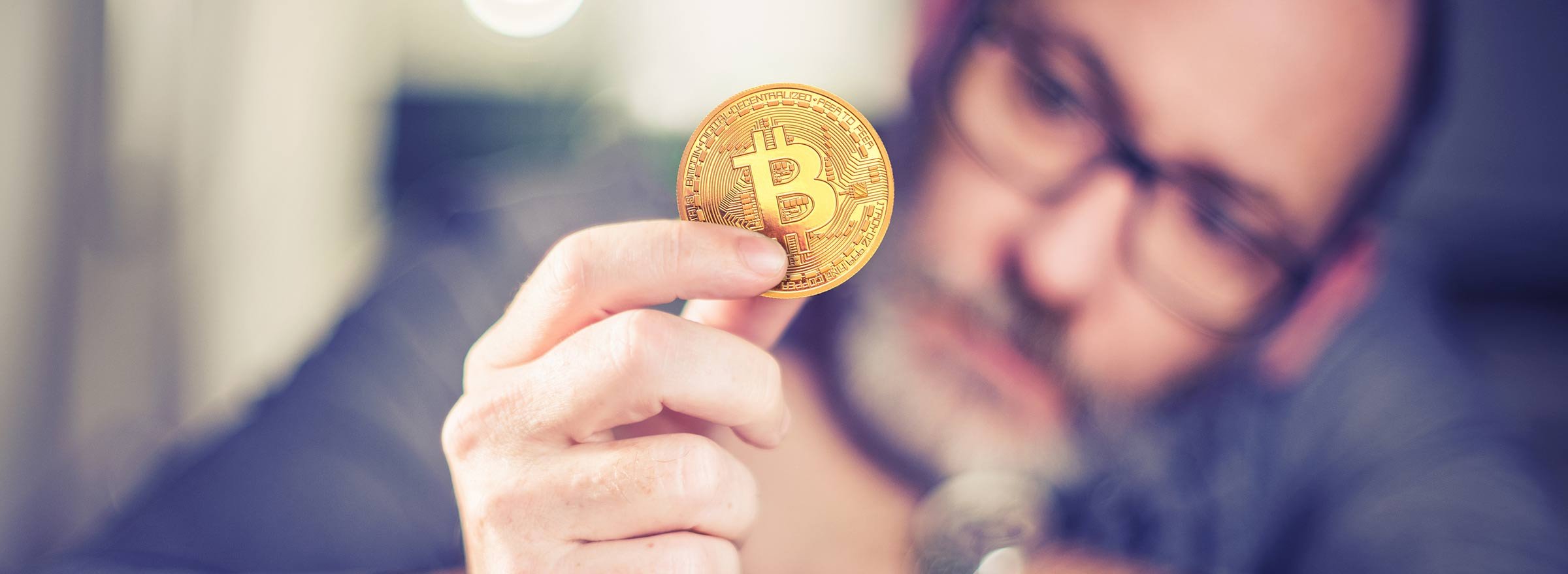 man holding a gold disc with a Bitcoin symbol on it