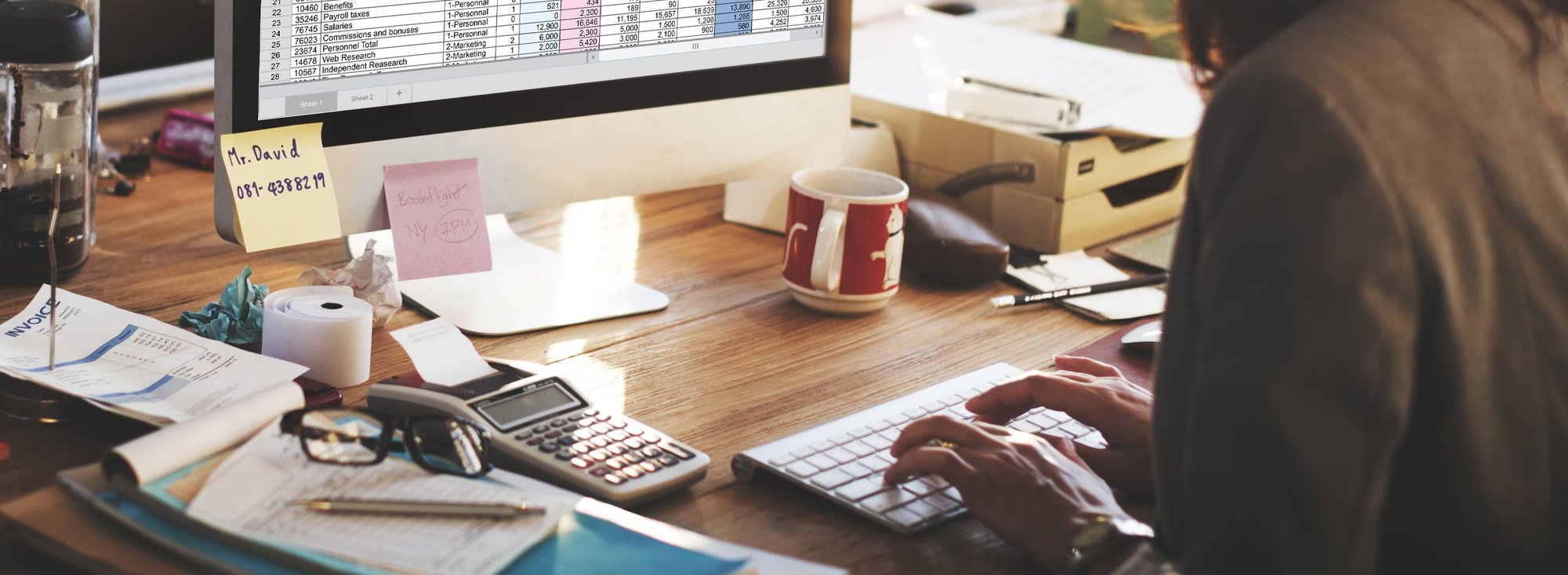 accountant using QuickBooks at a cluttered desk 